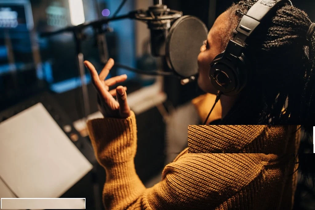 Vocalist wearing headphones recording into a studio microphone